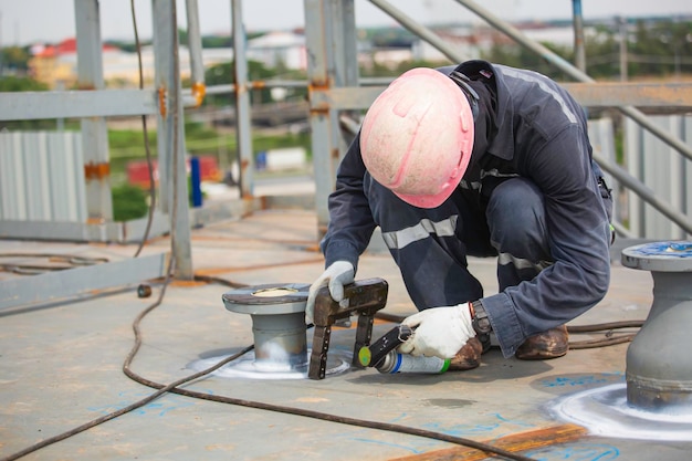 Male worker test nozzle tank butt weld carbon roof plate of storage tank oil background white contrast of magnetic field