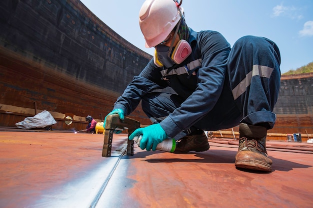 Male worker test steel tank butt weld carbon bottom plate of storage tank oil background white contrast of magnetic field test