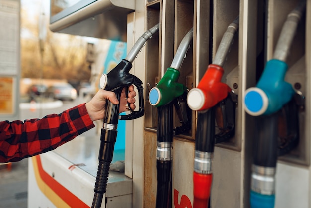 Male worker in uniform takes a gun at gas station