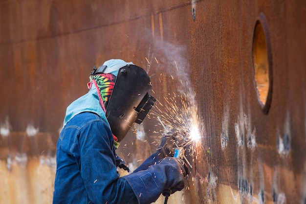 Male  worker wearing protective clothing and repair welding spark shell plate industrial construction oil and gas or  storage tank inside confined spaces.