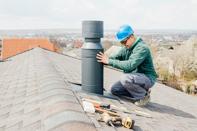 male worker with blue helmet installs an iron chimney worker 