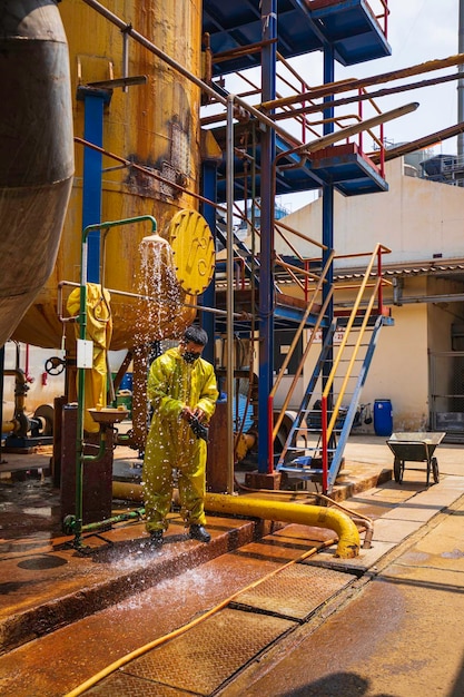 Male workers dressing in protective shower detoxification suit clean up after sealing a leaking container from corrosive toxic