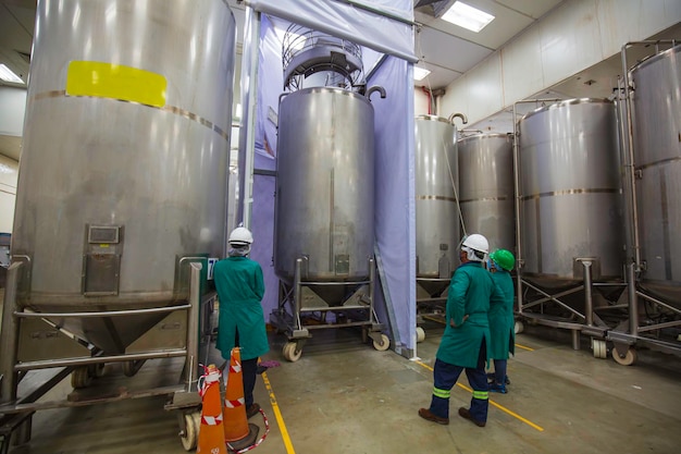 Male workers inspected stainless vertical steel tanks with equipment tank chemical cellar at the stainless tank