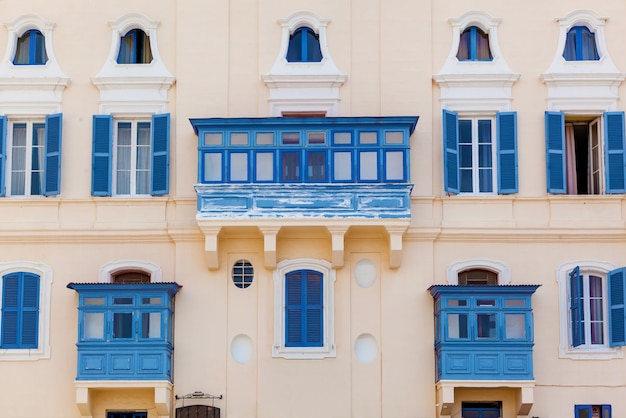 Malta architecture, facade of a house with wooden windows and a blue balcony on the island of Malta