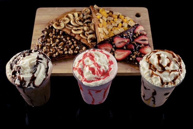 Photo malted milkshakes of different flavors and crepes dark background