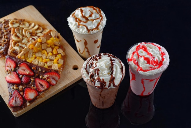 Photo malted milkshakes of different flavors and crepes dark background