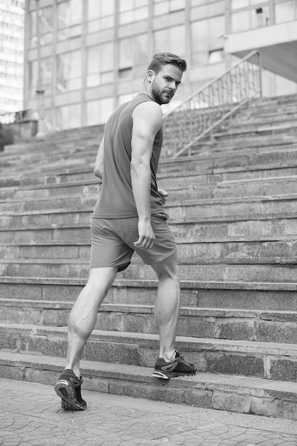 Man in active wear and sneakers on steps Sportsman workout on stairs Fit and confident Future and success Ready to overcome any obstacle Sport and training activity