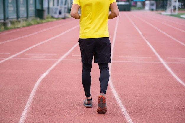 Man in activewear energetically running and jogging on the stadium track active and healthy