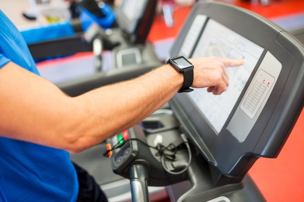 Man adjusting the settings of a treadmill