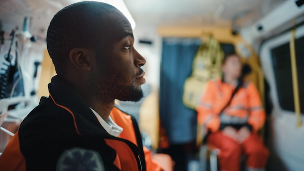 A man in an ambulance with a man in orange and black uniform sits in a helicopter.