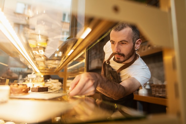 Man in apron arranging cookies in display