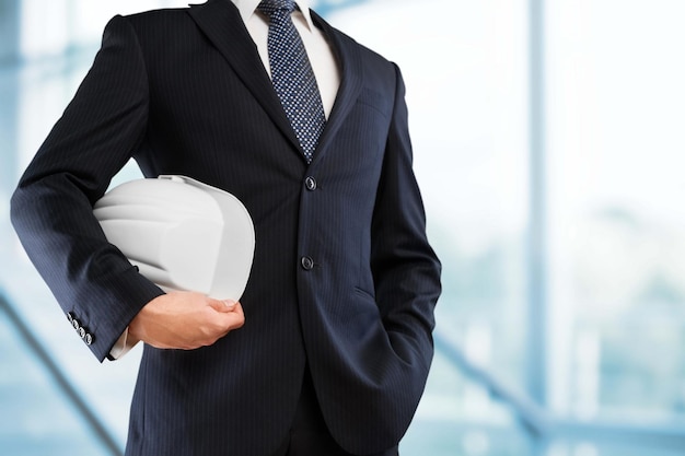 Man architect in suit holding helmet in hand