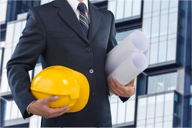 Man architect wearing suit holding blueprint and helmet