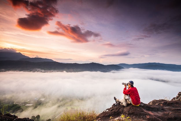 The man are taking photos  the sea of mist on high mountain.