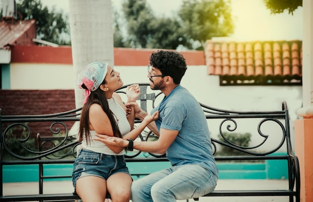 Man arguing with girlfriend sitting in a park Young couple arguing sitting on a park bench Concept of aggressive couples in the park Upset couple arguing on a park bench