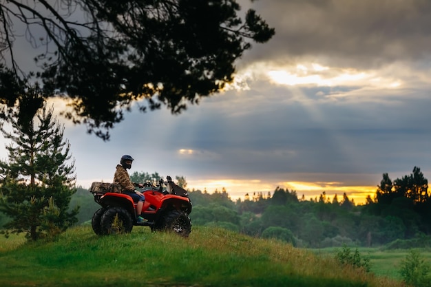 Man on the atv quad bike running at sunset