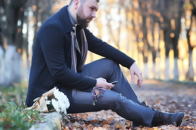 Photo man in autumn park outdoor with bouquet flower date waiting