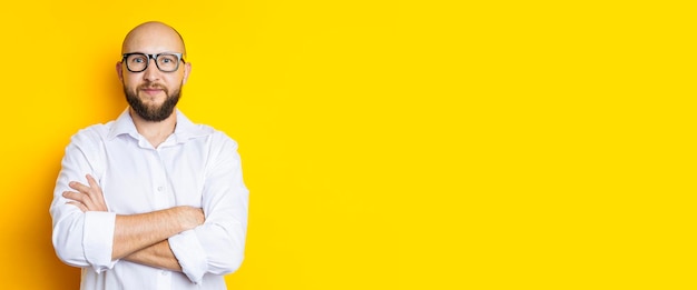 Man bald with a beard in glasses in a white shirt on a yellow background Banner