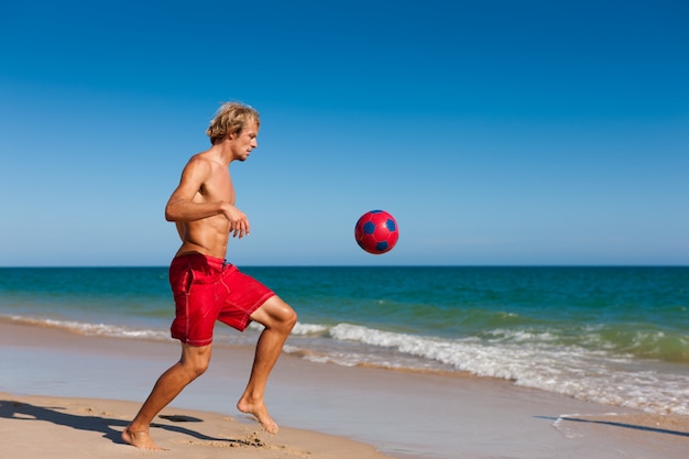 Man on beach playing soccer