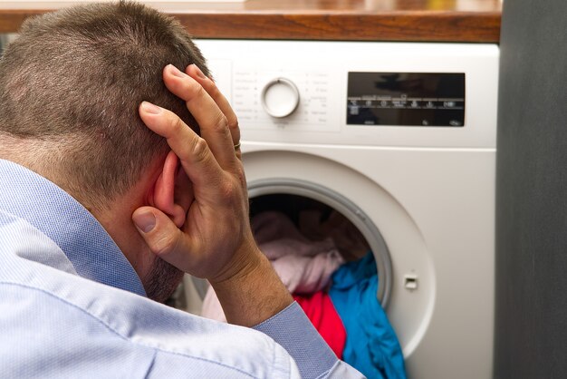 Man being worried about the washing machine, because it doesn't work.