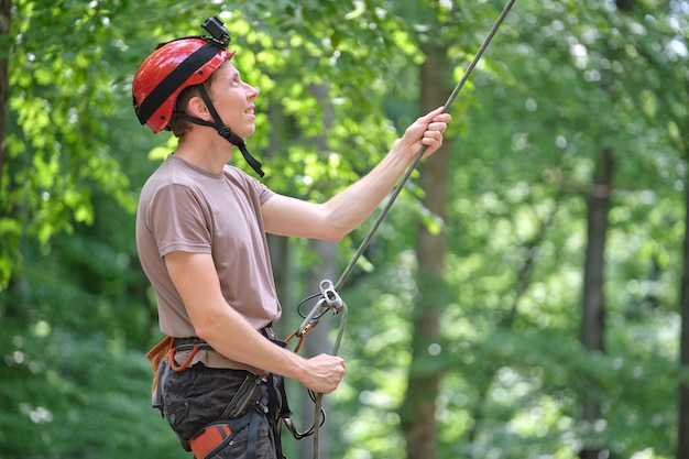 Man belays his partner climber with belaying device and rope. Climber's handsman holding equipment for rock mountaineering security.