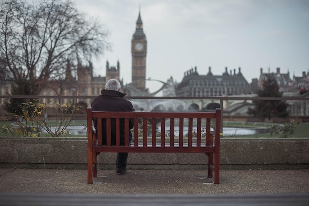 Photo man on bench in city against sky