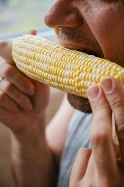 A man bites a cob of corn closeup of an unrecognizable man