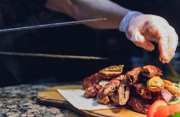 Man in black gloves put lamb with spatula for food on white plate Tasty cooked brown meat of lamb