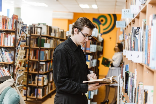 Man in a black shirt choosing a book in the library