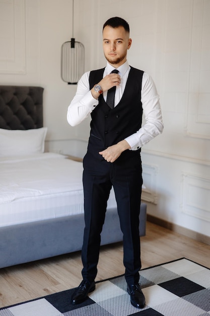 Photo a man in a black suit is standing in front of a bed