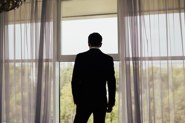 man in black suit standing near the panoramic window