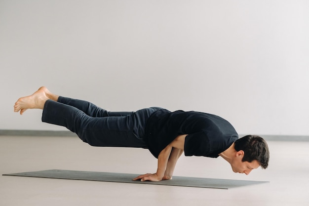 A man in a black T-shirt trains lying down doing stretches in the gym.