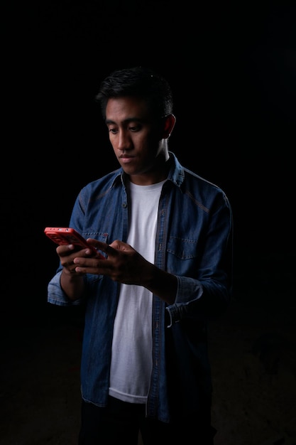 A man in a blue shirt is holding a red phone.