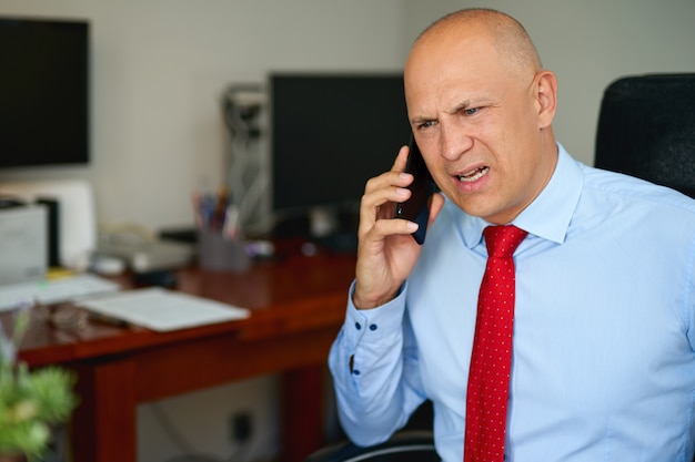 Man in blue shirt and red tie at office