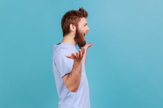 Man in blue Tshirt standing with raised hands and indignant face asking why annoyed by problem