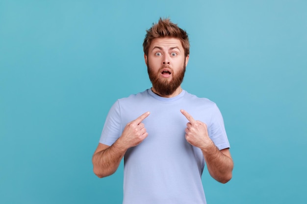 Man in blue Tshirt staring in amazement at camera and pointing herself shocked by sudden success