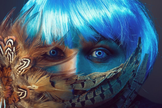 Man in blue wig behing feathers