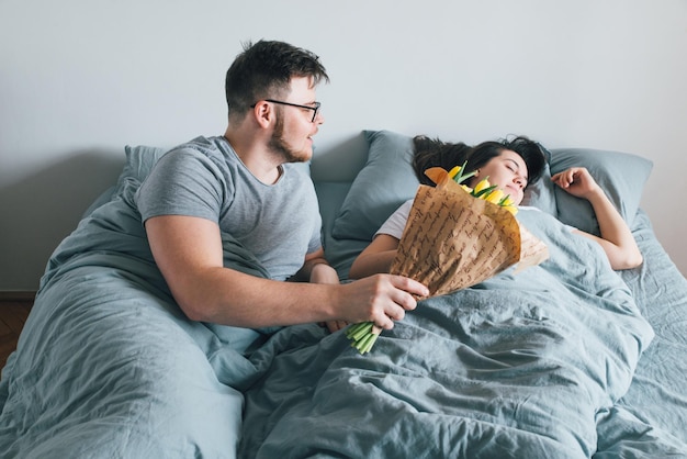 Man bring flowers in bed surprise for girlfriend in the morning romantic concept