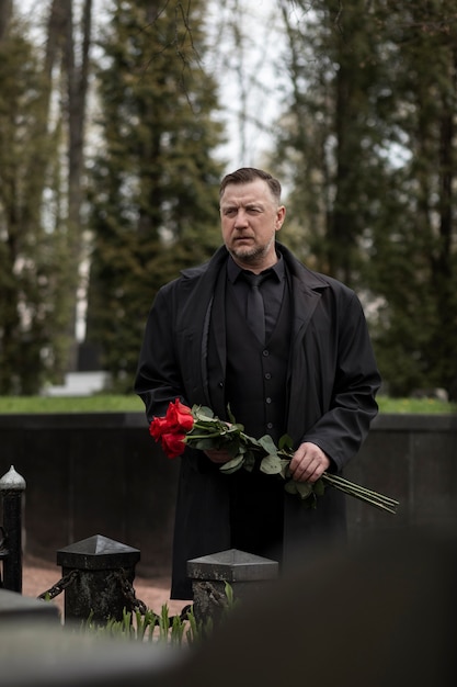 Man bringing roses to a gravestone at the cemetery