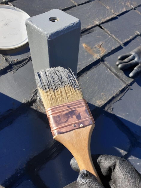 Man brush painting a metal pole gray