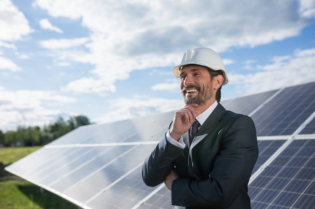 Man in business suit happily smailing, solar panels on backstage.