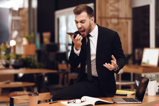 A man in a business suit talking loudly on the phone.