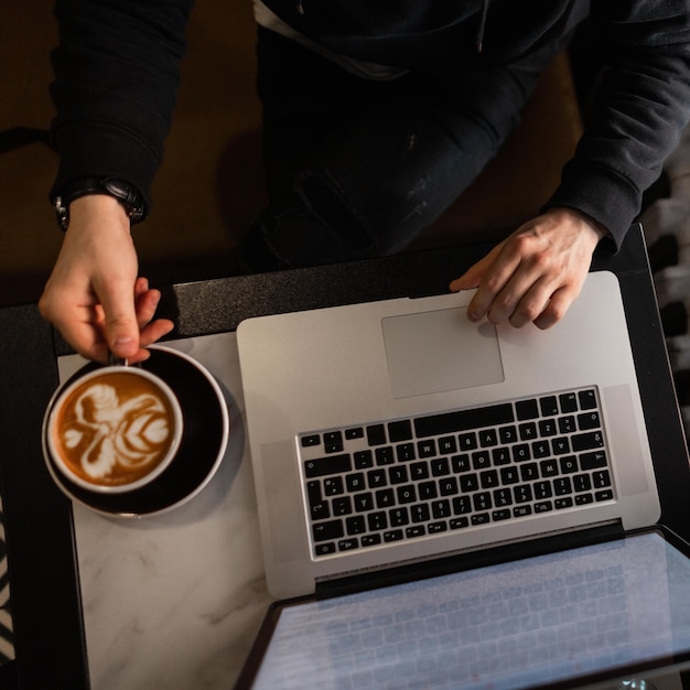 Man businessman working at laptop and drinking coffee, top view