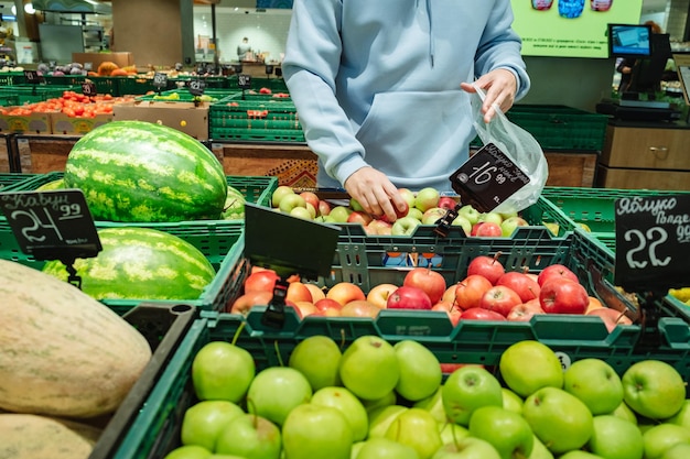 A man buys food A male customer chooses apples taking products from the shelves