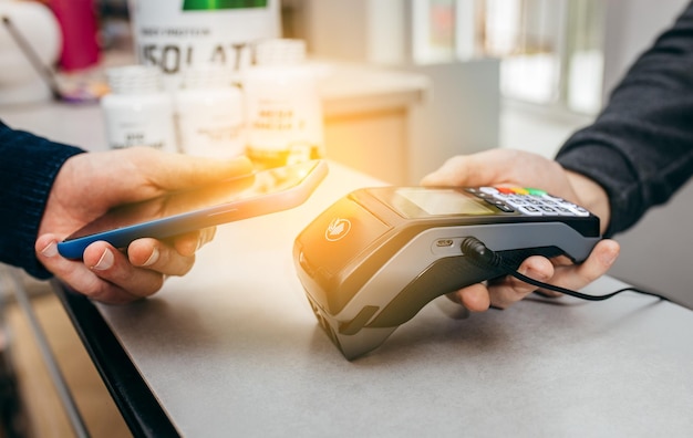 A man buys a set of sports nutrition Payment transaction with smartphone in market Male hand with