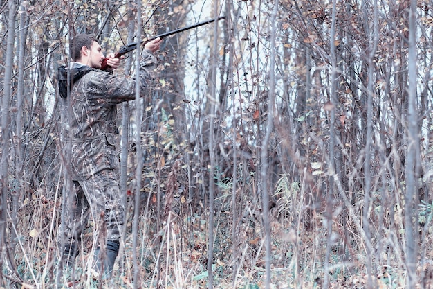 Man in camouflage and with a hunting rifle in a forest on a spring hunt