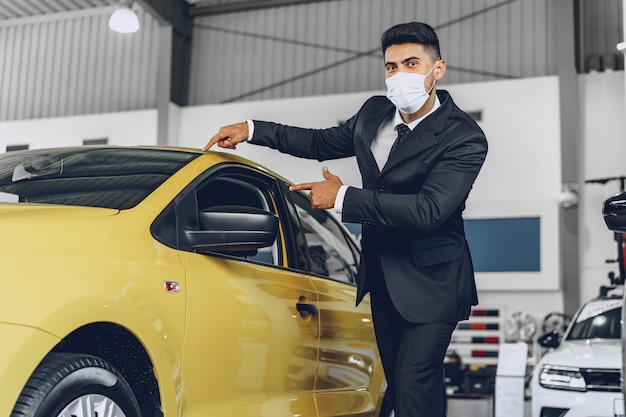 Man car dealer wearing protective medical mask on his working place