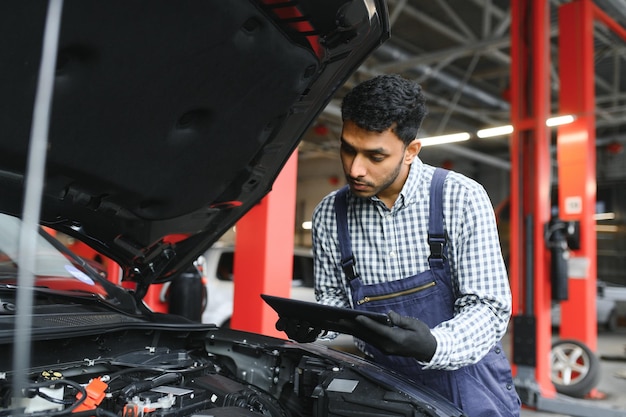 Man car technician mechanic repairing car problem of engine during system checking detail using tablet computer for maintenance and fixing in car garage