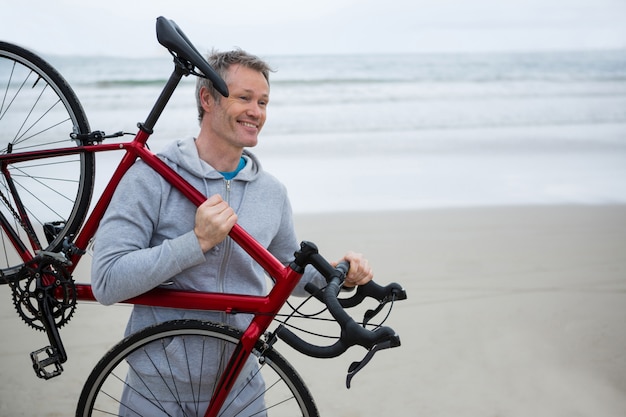 Man carrying bicycle on beach