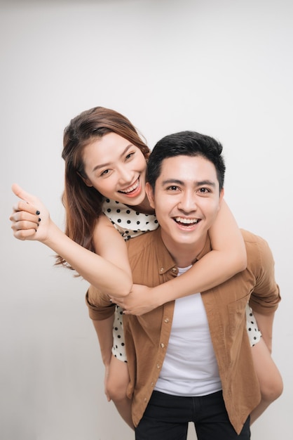 Man carrying his lover on back woman showing peace symbol over white background